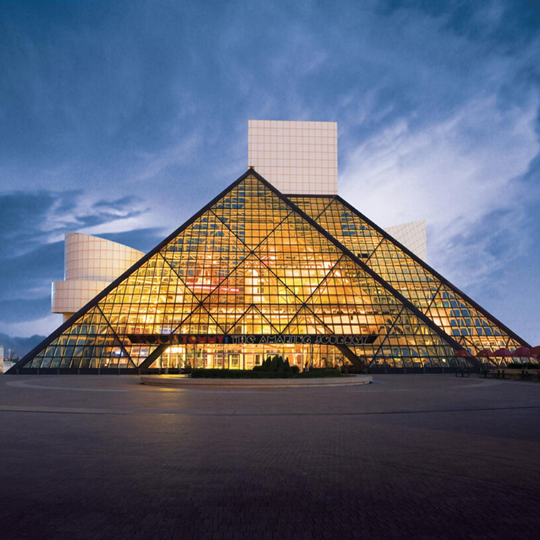 Rock & Roll Hall of Fame building with illuminated glass pyramid architecture at dusk.