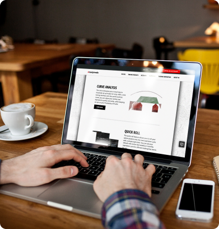 Person using a laptop at a café table, viewing a stock trading website with analytics tools and trading features.
