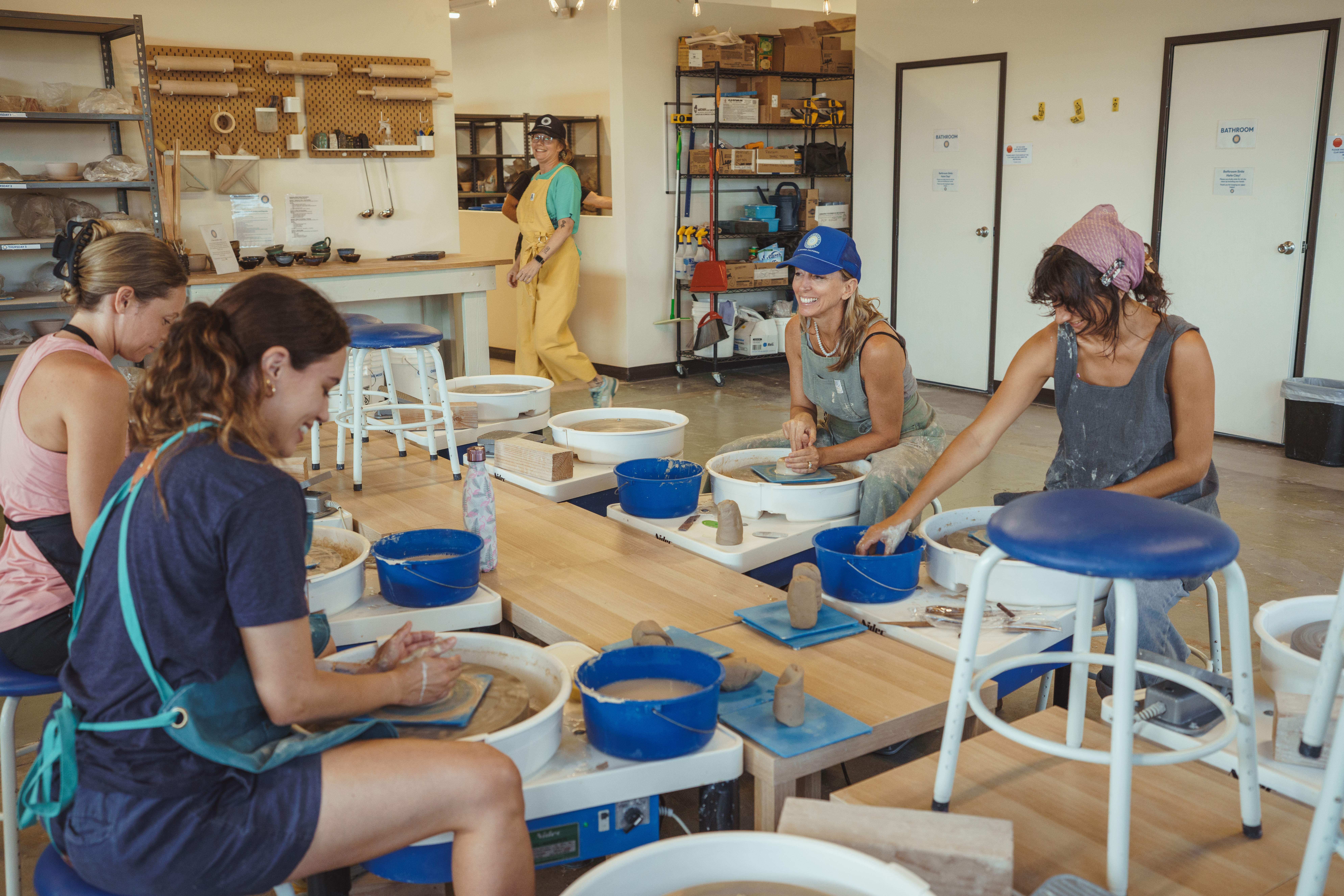 Nancy laughs with members of the studio community at the pottery wheels. Creating a place to connect has become as important as the ceramics themselves.