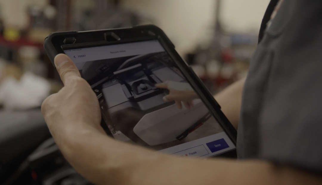 A A technician holding a tablet showing a Quik video he has just created