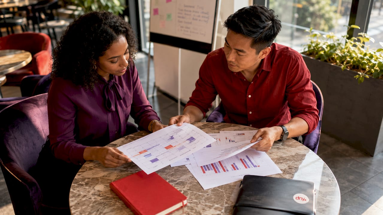 Des collaborateurs échangent des documents autour d’une table de réunion, illustrant un travail d’équipe efficace.
