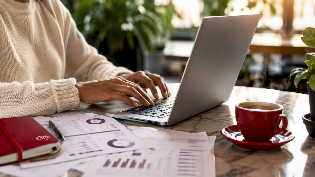 Des mains s'activent sur un clavier, analysant des rapports du marché de la fintech.