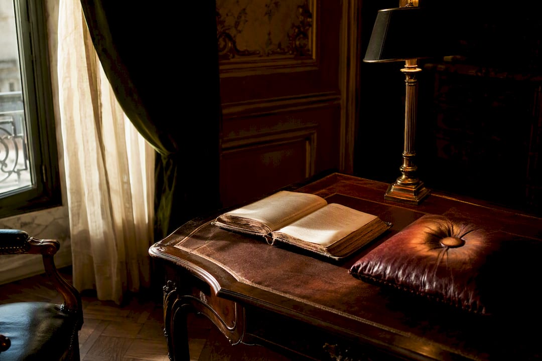 Un vieux livre en cuir posé sur une table en bois, baigné par la lumière douce d’une lampe.