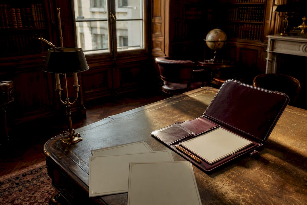 Protège-documents en cuir et certifications posés sur un bureau en bois