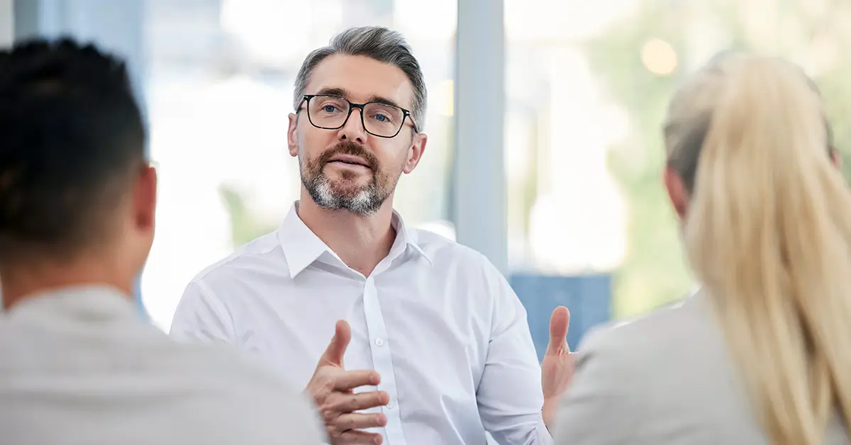 Business leader facilitating a discussion with colleagues in a modern office, representing real-world leadership and collaboration in implementing agentic AI in legal operations.