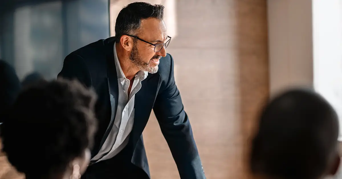 Business executive leading strategy meeting with team in modern office discussing enterprise AI strategy, ecosystem thinking and high-value use cases.