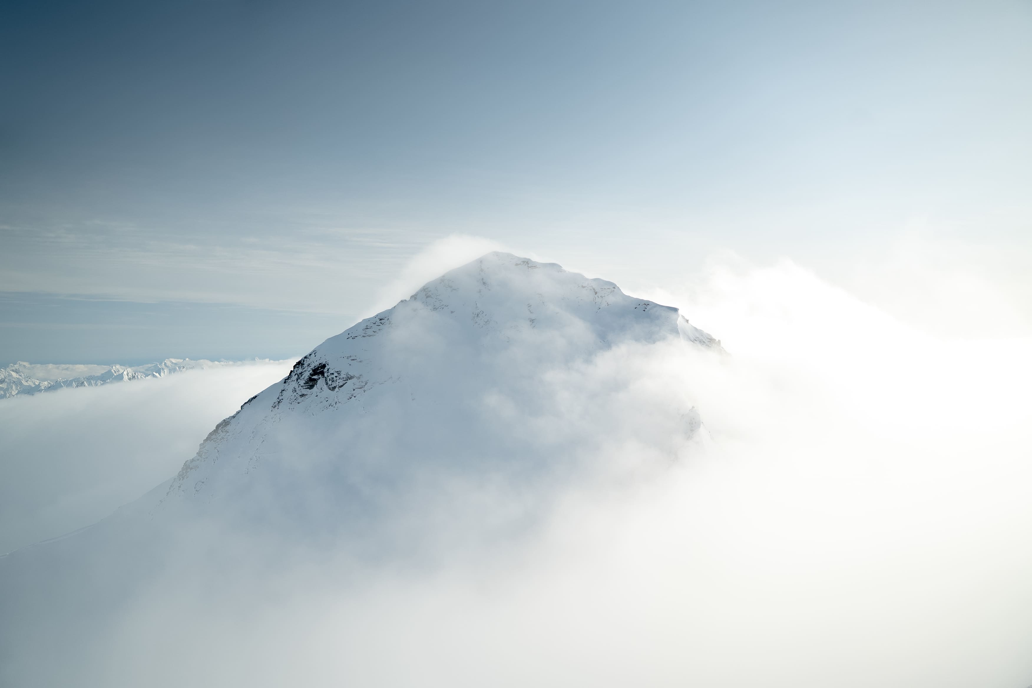 a beautiful mountainous view of mountains in Alaska with clouds covering them.