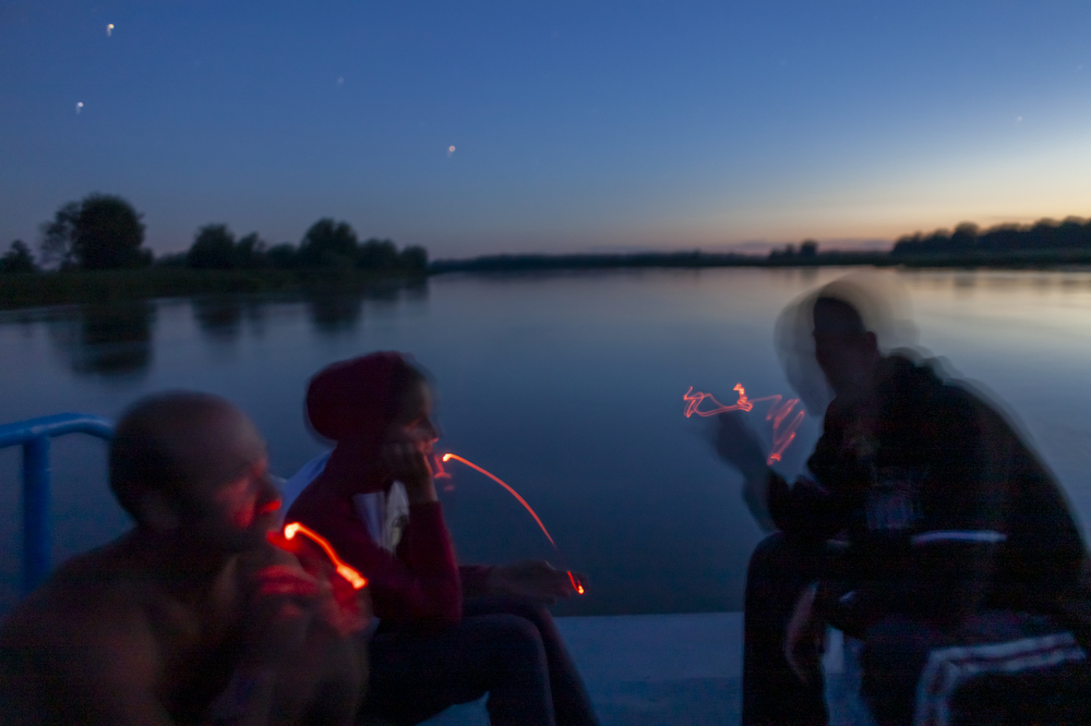 Crew of a transport ship, from left  Zbigniew Laskowski, Maria Szukalska, Łukasz Szymański rest on deck under starry sky.