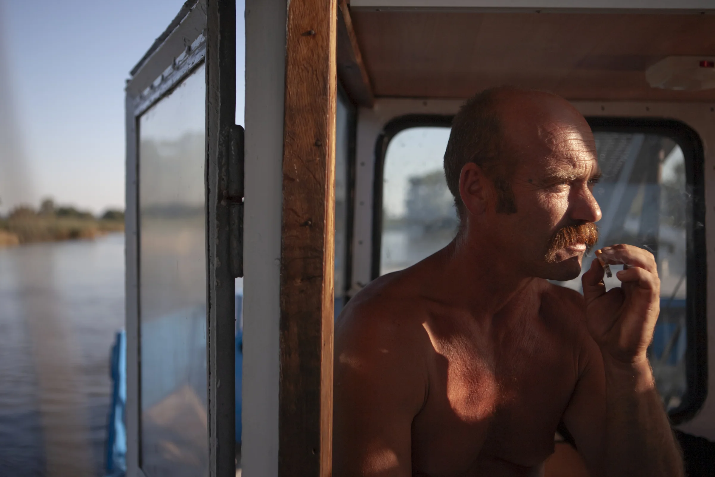 River sailor Zbigniew Laskowski smokes a cigarette in a ship's wheelhouse, during a transport cruise on the Odra river in Poland.