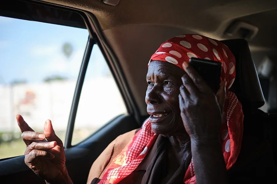 Shelta Nhengo, 75, a community health worker talks on a mobile device as she receives news of a new vehicle acquisition from one of her grandchildren residing in different neighbourhood.