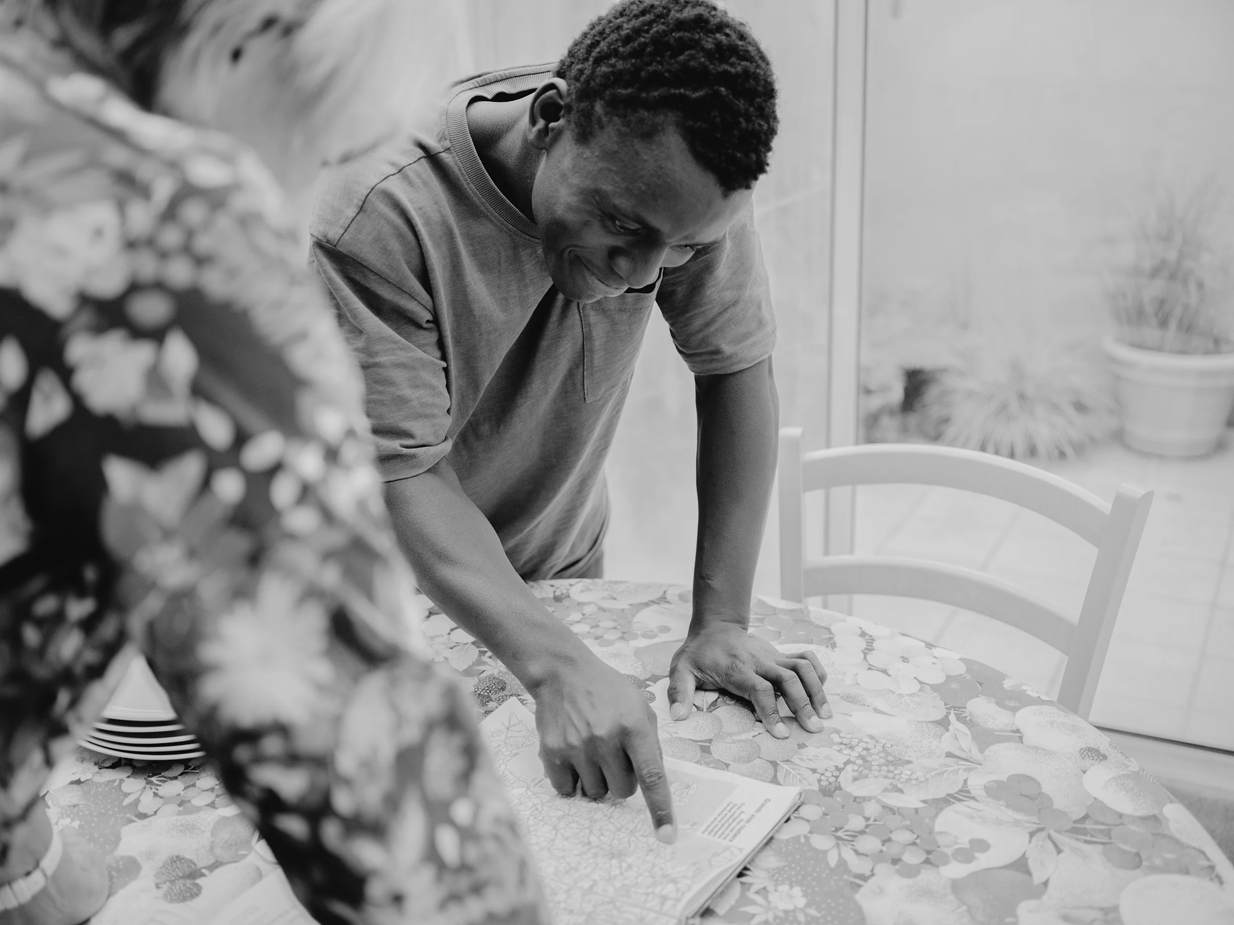 As they prepare lunch, Marianne unfolds a map of France to teach Ousmane how to read it, while he points out the places he passed through during his journey.
