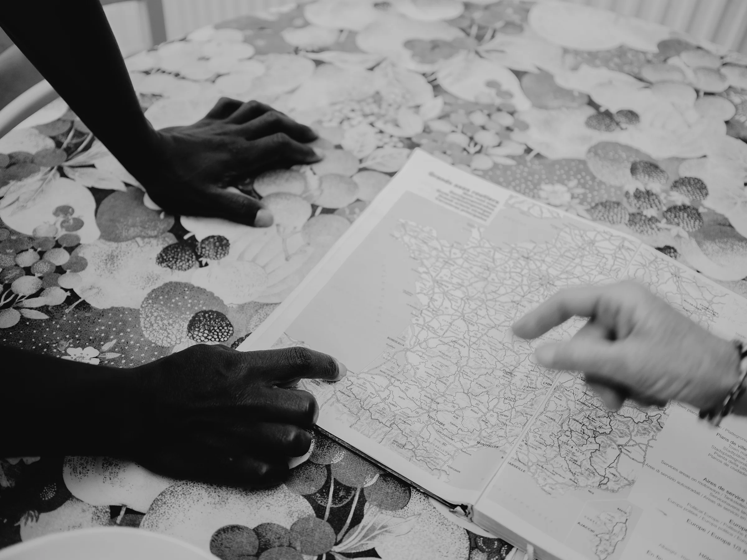As they prepare lunch, Marianne unfolds a map of France to teach Ousmane how to read it, while he points out the places he passed through during his journey.