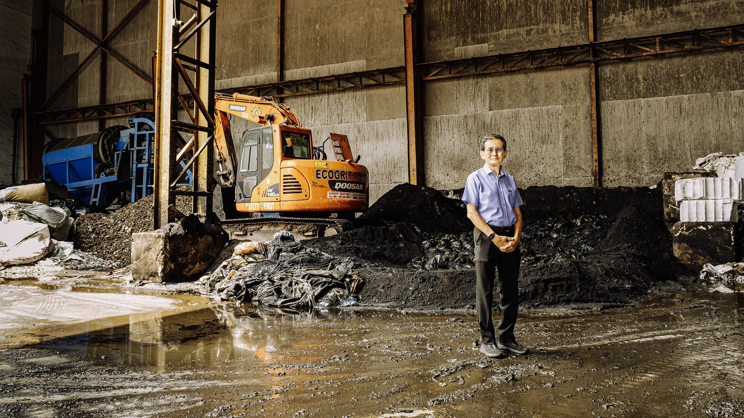 Gin Keat Ong shows the waste management processing facility that can process up to 500t/day. The pile of waste behind him is copper slag that is to be reused in a circular economy.
