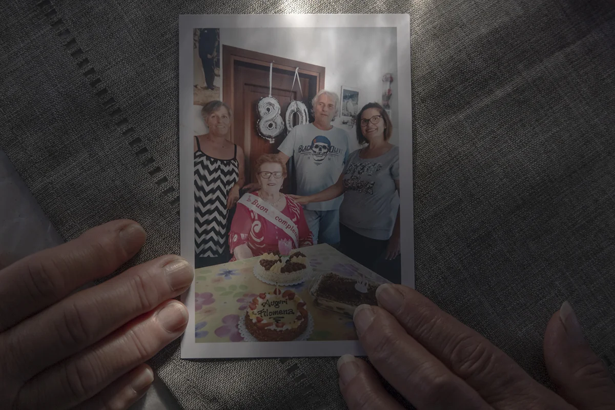 Barbara and Giovanna Tesserin hold a family photo of their mother, one of the first fisherwomen in the village, who passed away in 2023.
