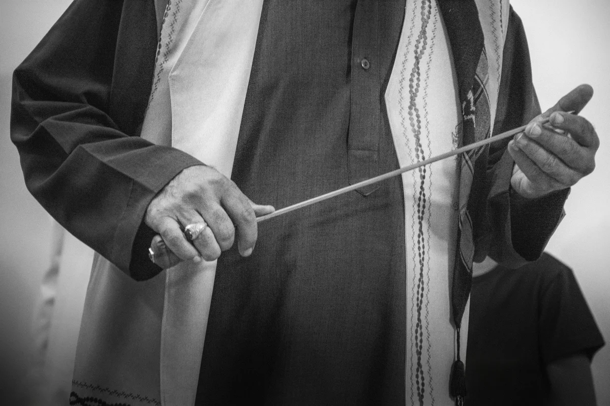 The Caliph holds a dagger during the ritual. The Caliph guides and assists the dervishes during the ritual.