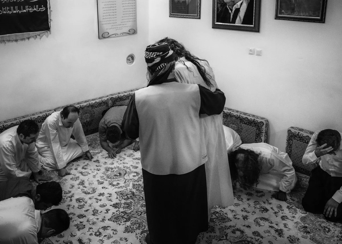 A caliph helps a dervish to sit up and recover after a period of intense dhikr.