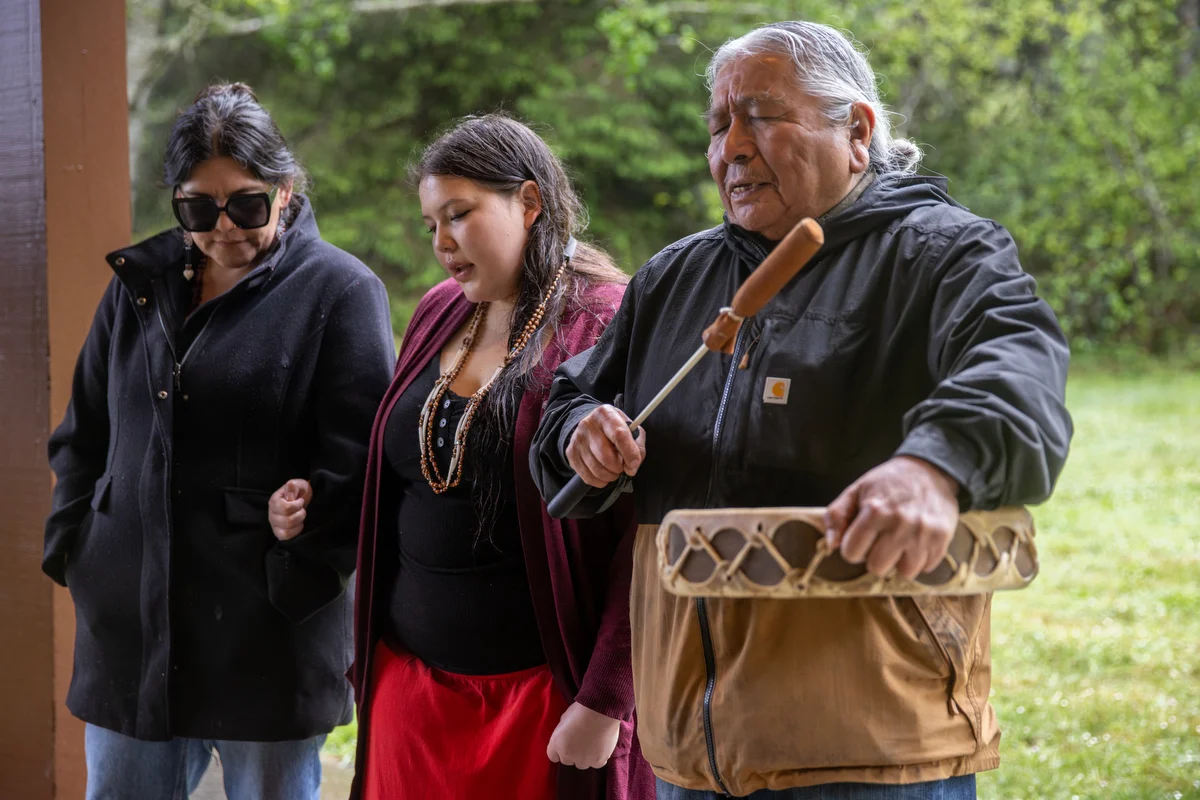 An elder leads song and prayer with a drum.
