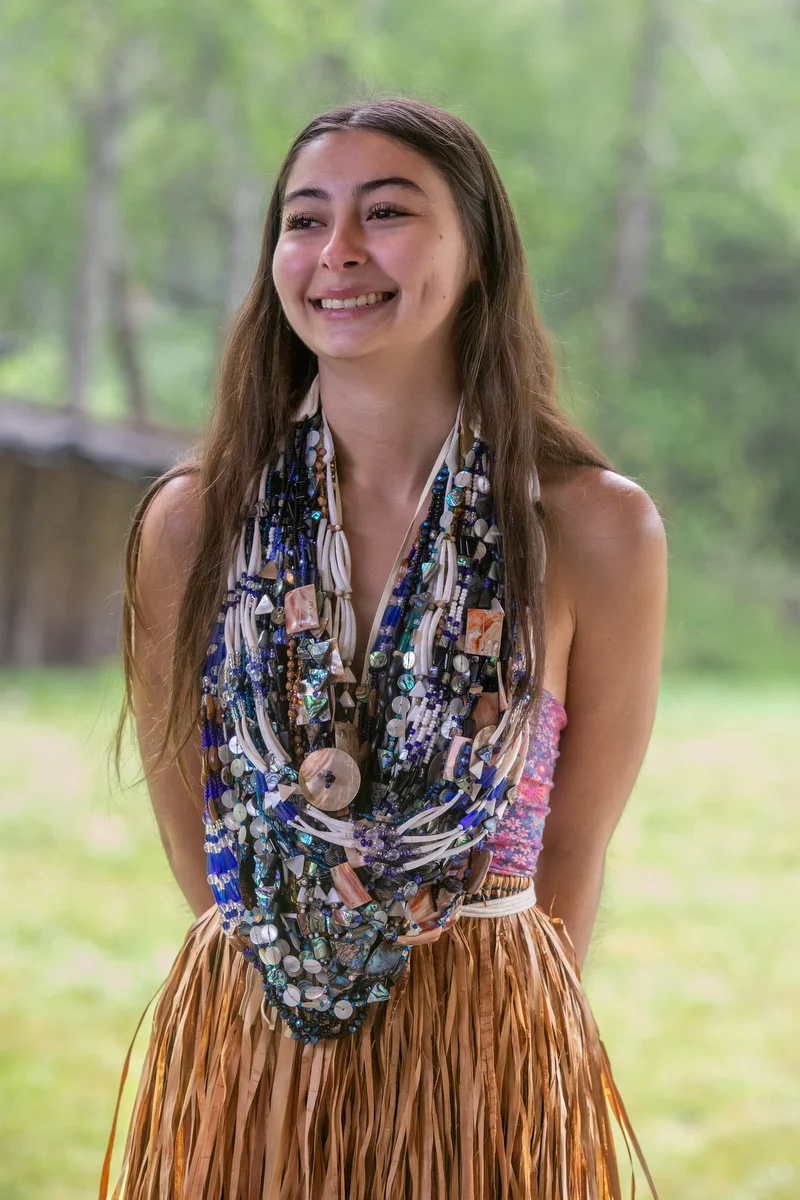 A young woman stands in regalia after preparing for the Flower Dance.