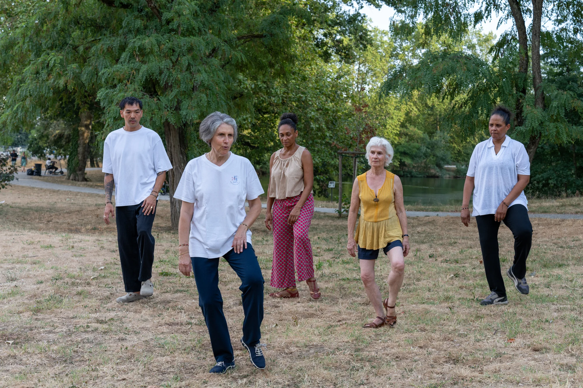 Camille Bonnamour trains Qi-Gong with a group in a city park.