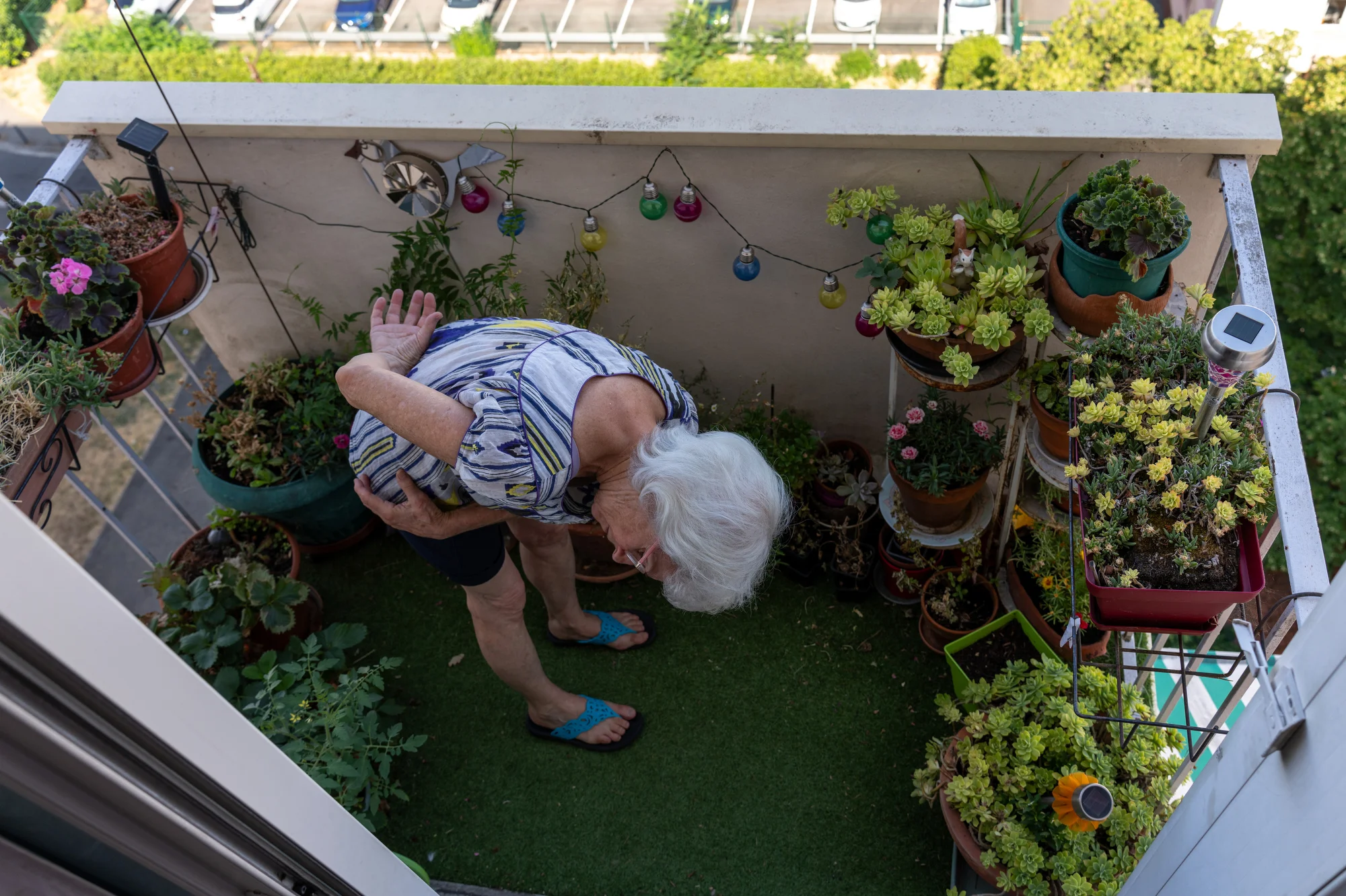 She does Qi-Gong on her small balcony decorated with ornamental plants and flowers.