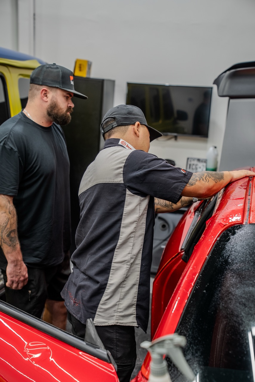 Two paint protection film installing technicians adding PPF to a vehicle