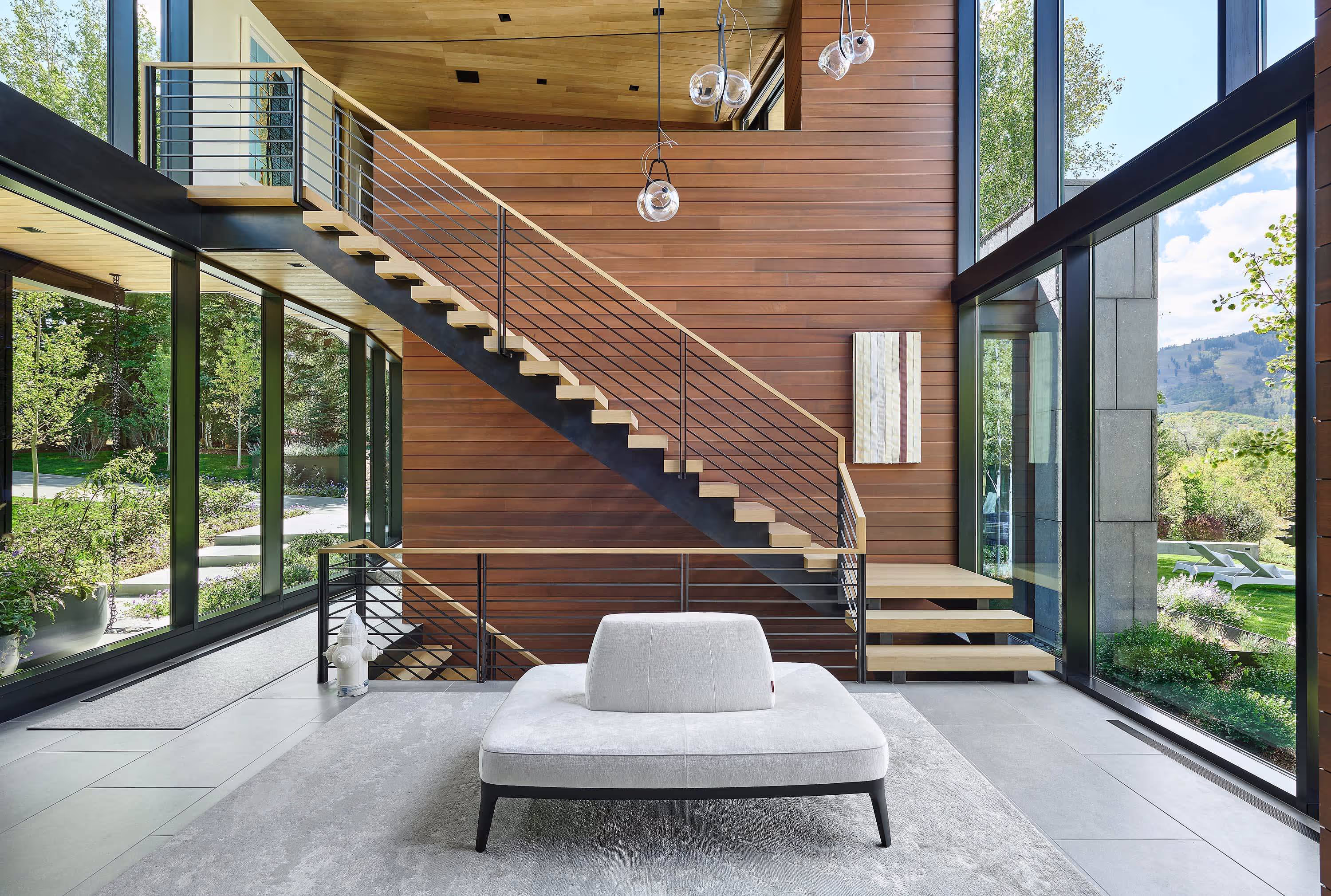 Modern metal and wood staircase with big windows that span from floor to ceiling