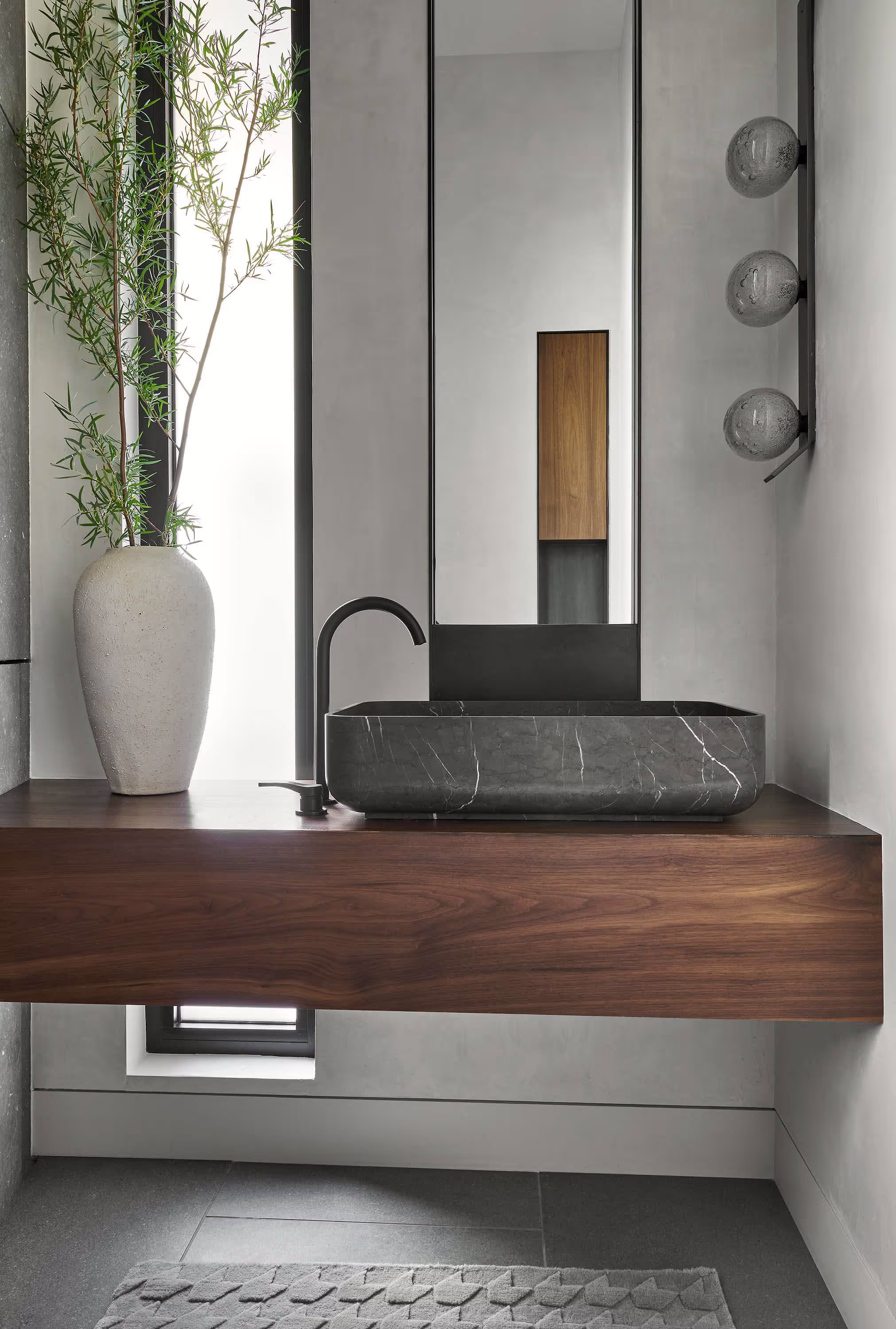 Floating wood vanity with a carved stone sink