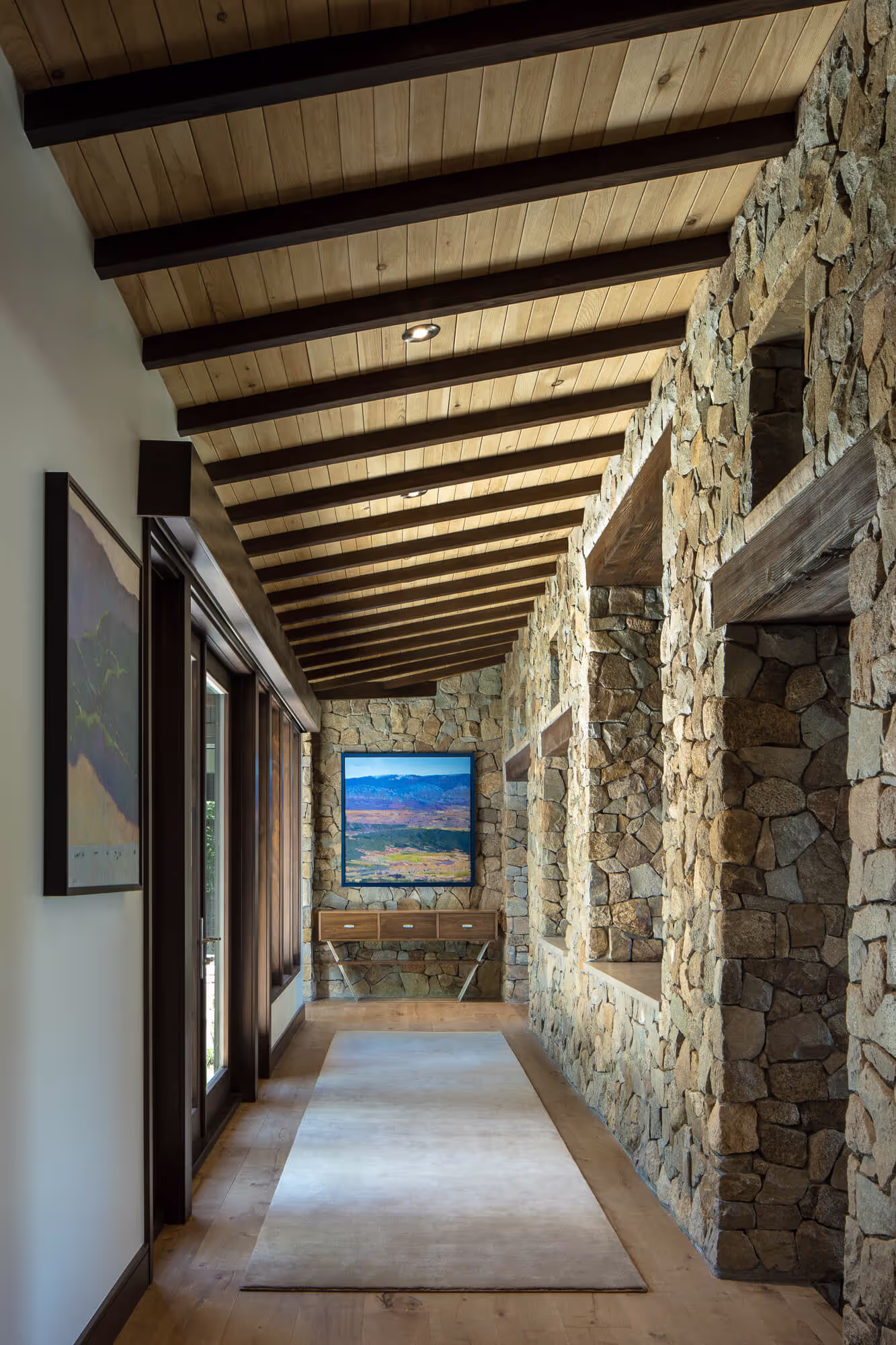 Hallway with an exposed wood ceiling and wall made of stones
