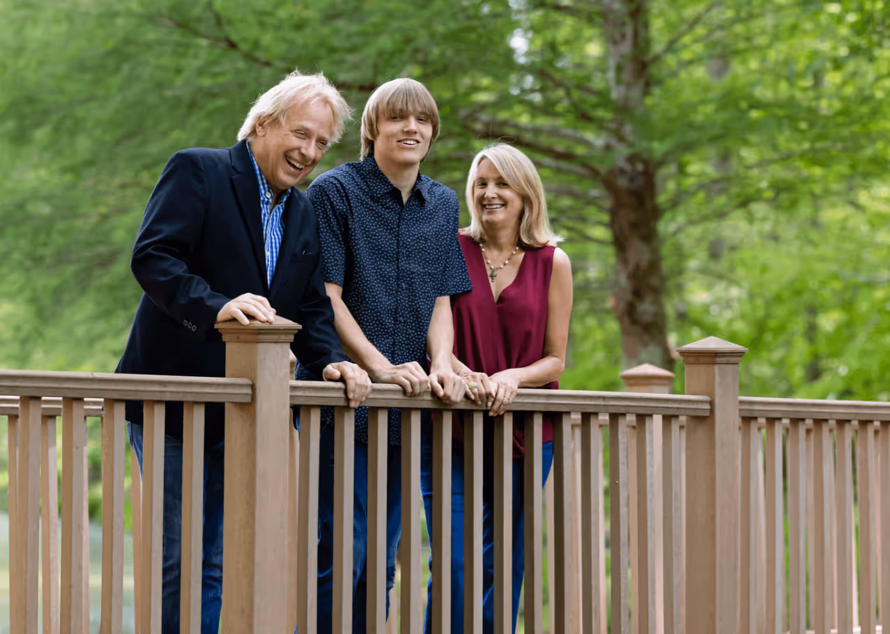 Dad and mom laughing with child on bridge