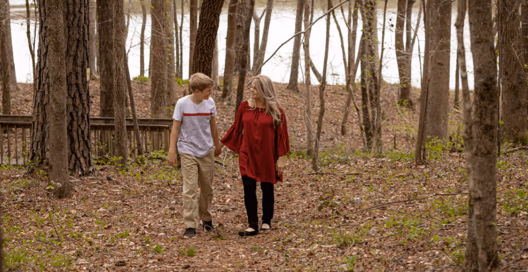 Mom and son walking on a wooded path in fall.