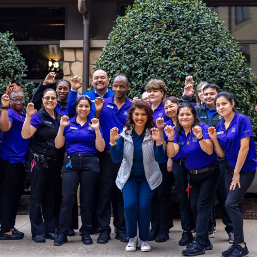 Dr. Romie Mushtaq posing with a group of Pack Members giving the Paw sign