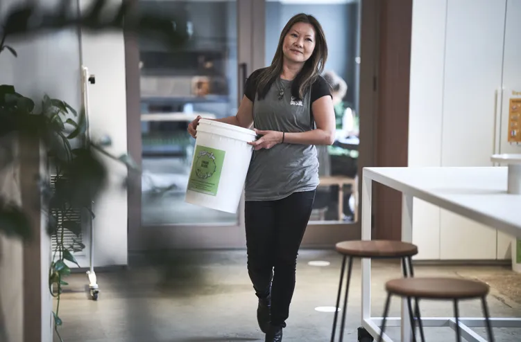 Founder of Cirque du Soil carrying food scraps in bucket from a cafe for composting.