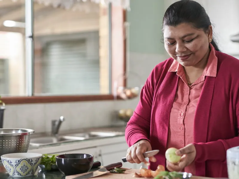 A woman chops vegetables in the kitchen