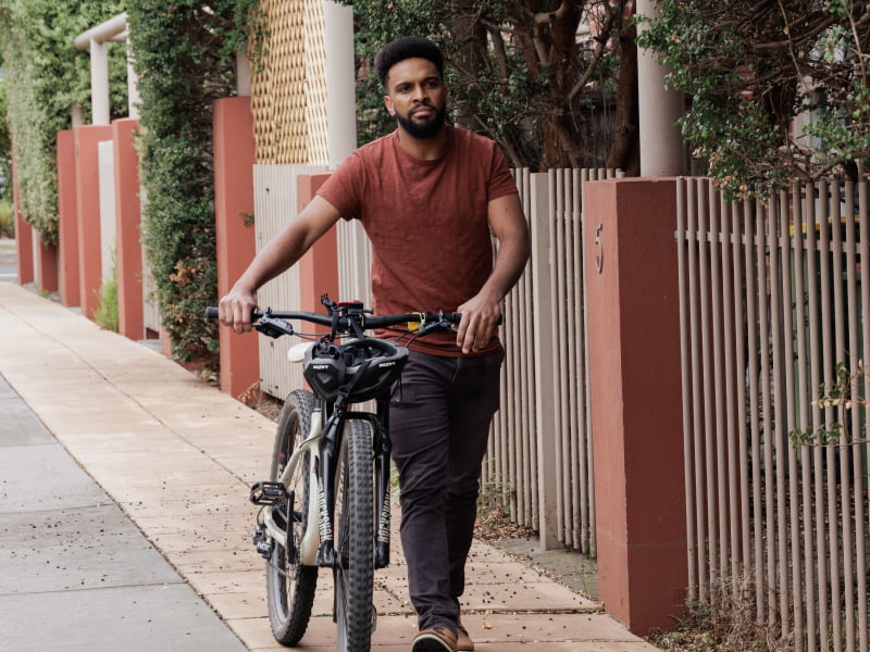 A man pushing his bike across a road