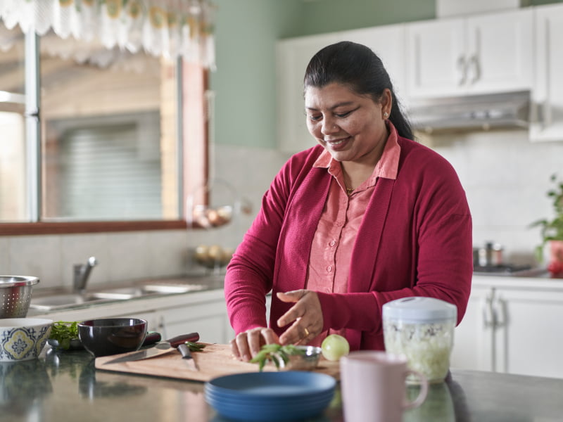 A woman cutting vegetables in her kitchen