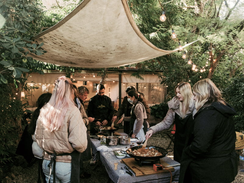 A gathering of people cooking together on portable stoves outside