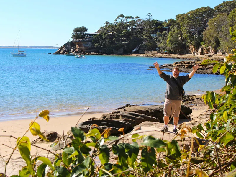 A man stands at the beach waving both arms in the air