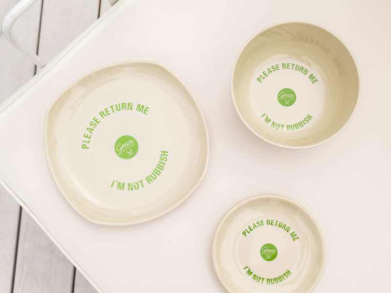 Three bowls that say "Please return me, I'm not rubbish" are placed on a white table