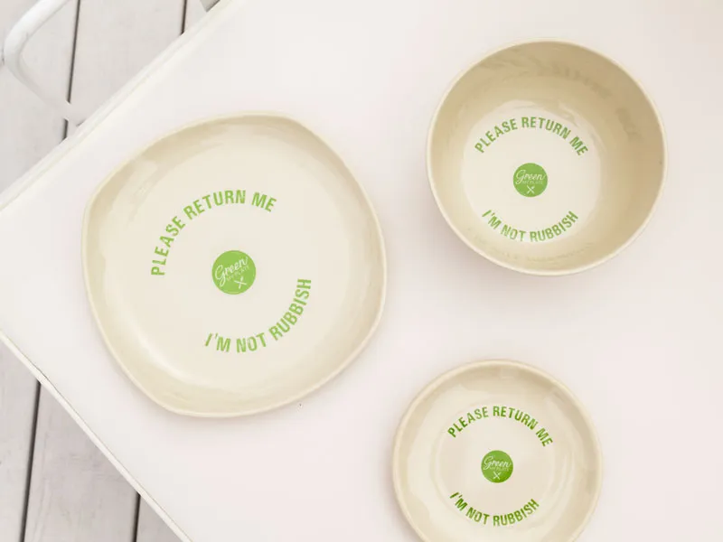 Three bowls that say "Please return me, I'm not rubbish" are placed on a white table