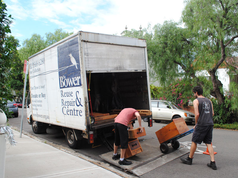 Two people load wooden drawers onto a truck