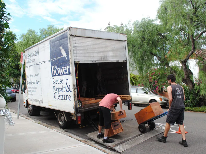 Two people load wooden drawers onto a truck