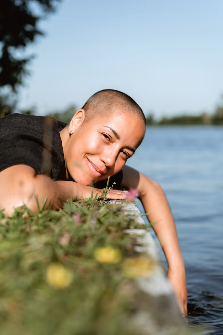 Vrouw ligt op de kade met haar hand in het water.