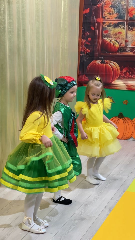 Drei Mädchen in gelbgrünen Gemüsekostümen bereiten sich auf ihren Auftritt an der Schule „Kinder der Zukunft“ vor