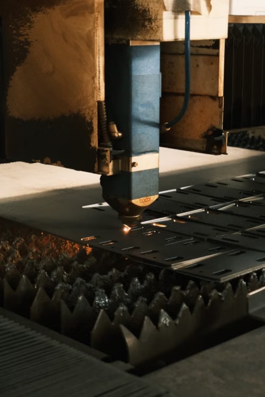 Laser cutting head cutting slots into a flat sheet metal blank on a fiber laser bed