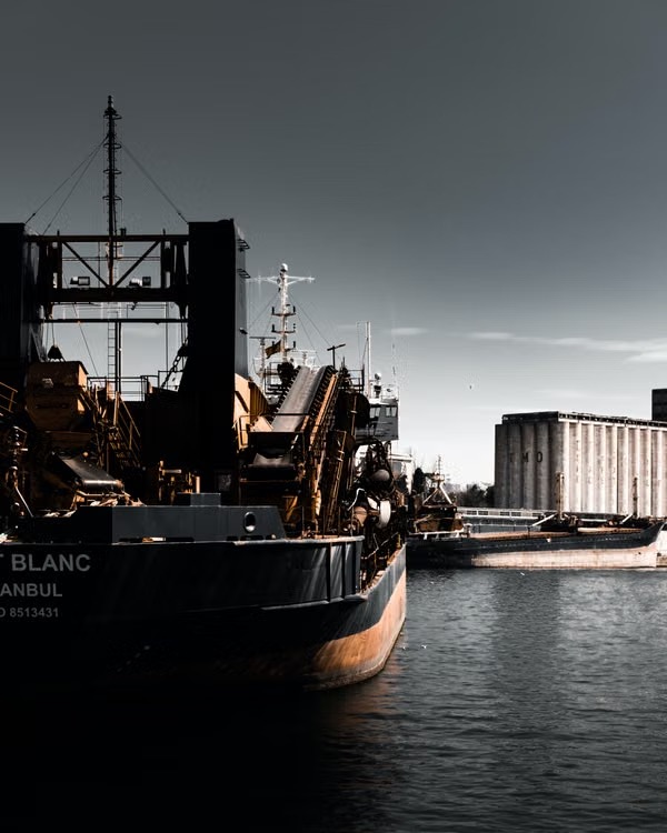 Cargo ship moored at a harbor beside grain silos at dusk