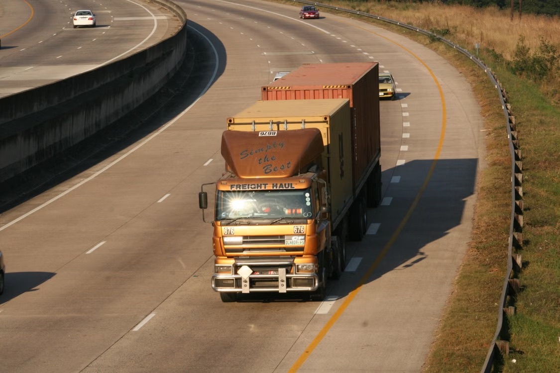 Freight truck hauling a shipping container along a highway