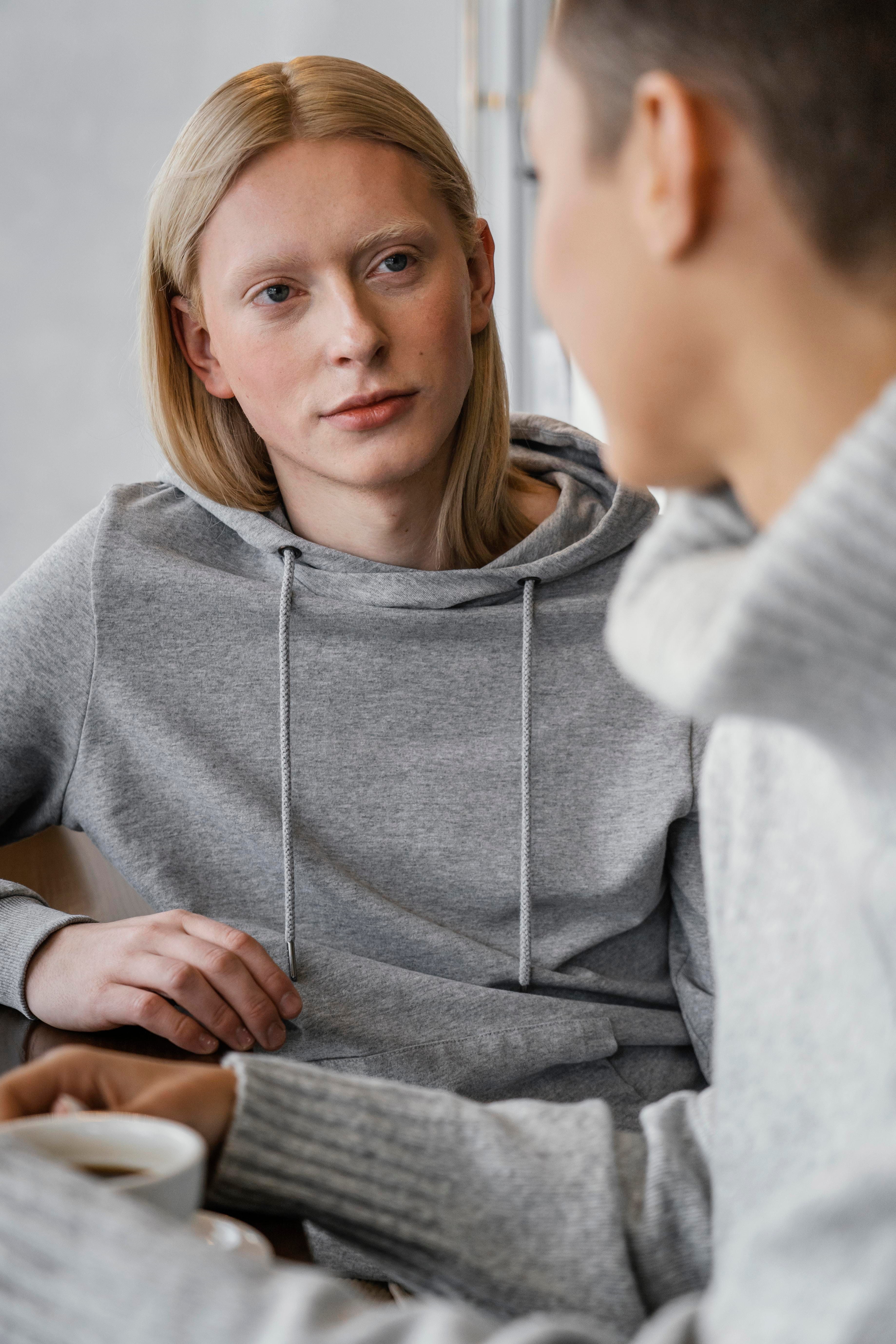 Blonde woman sitting down with another person who is off focus. 