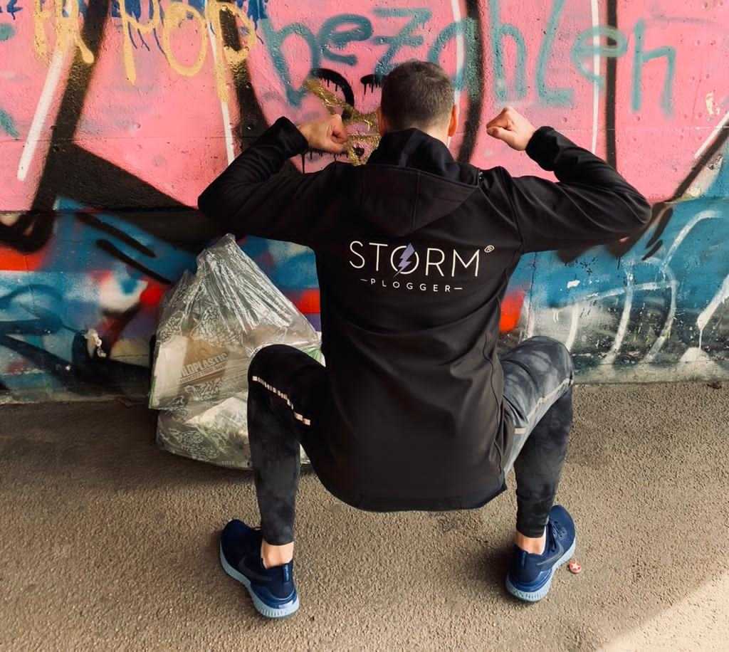 A STORM instructor squats in front of a concrete wall.