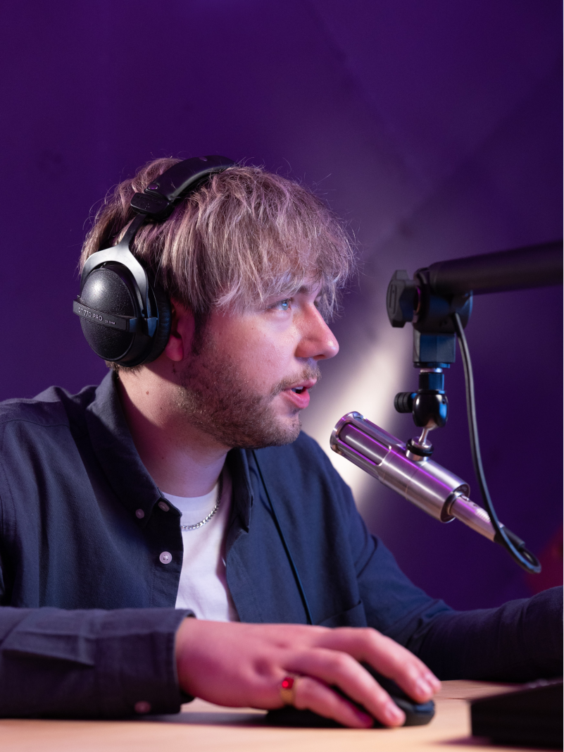 A man wearing headphones sitting in front of a microphone.