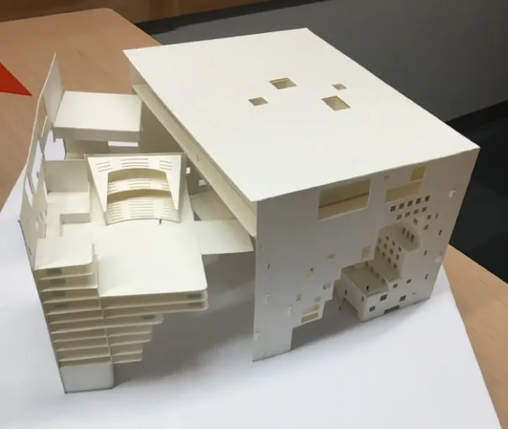 A plain paper model of a building with a slide out that showcases the interior
